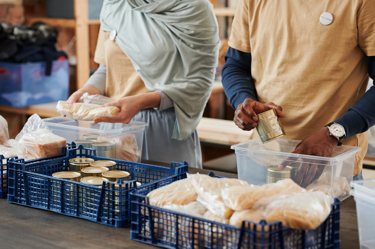 cta-02 Adults sorting food donations in containers for charity. Community service effort indoors.